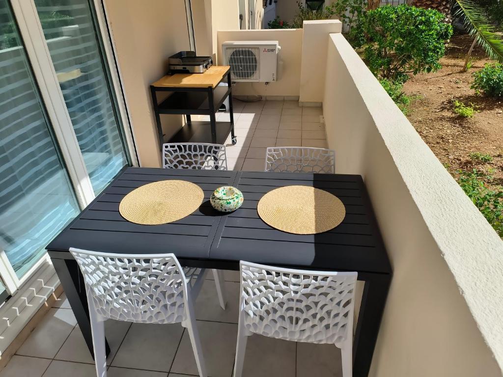 a black table and chairs on a balcony at Le Victoria-Centre ville-Piscine-Parking privé-Wi-Fi in Hyères