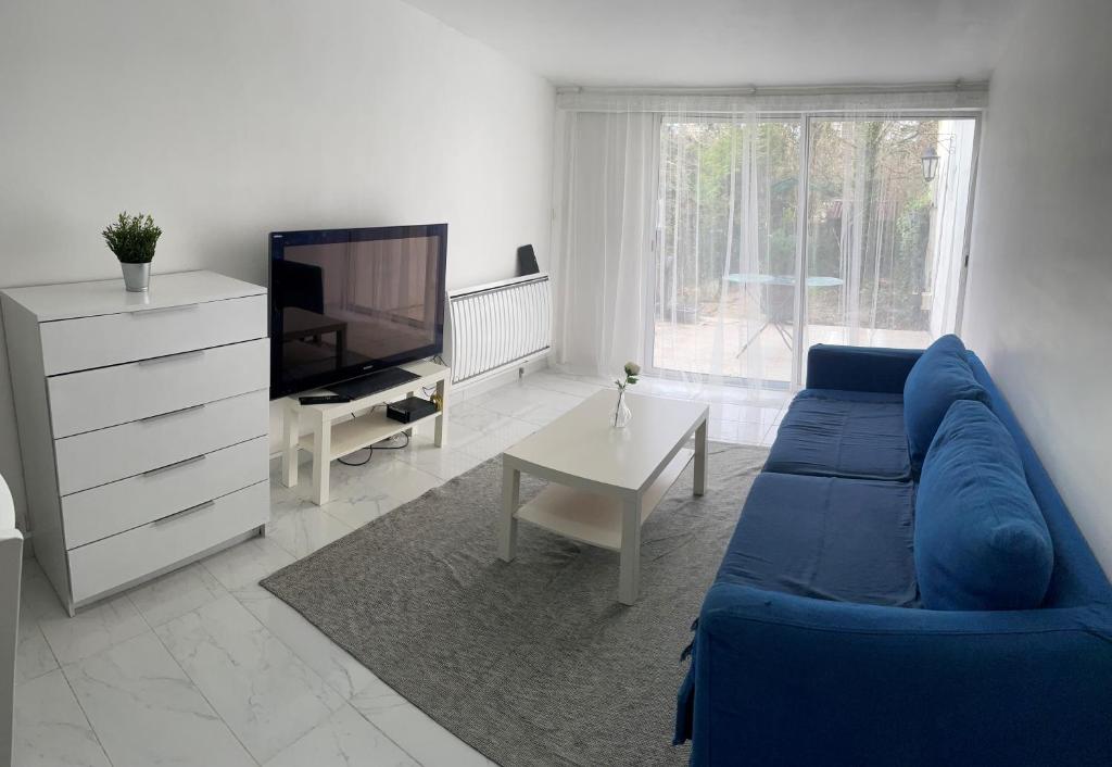 uma sala de estar com um sofá azul e uma televisão em Maison indépendante 7 minutes RER B em Antony
