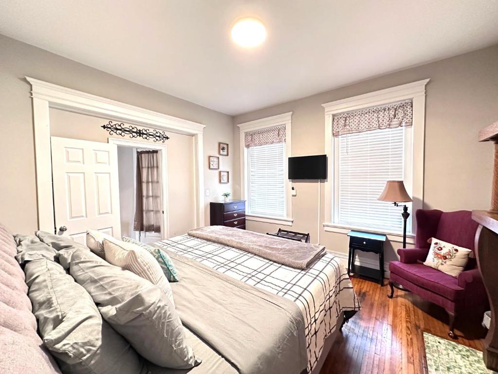 a bedroom with a bed and a chair and windows at Carytown nest King Bed fully fenced in Richmond