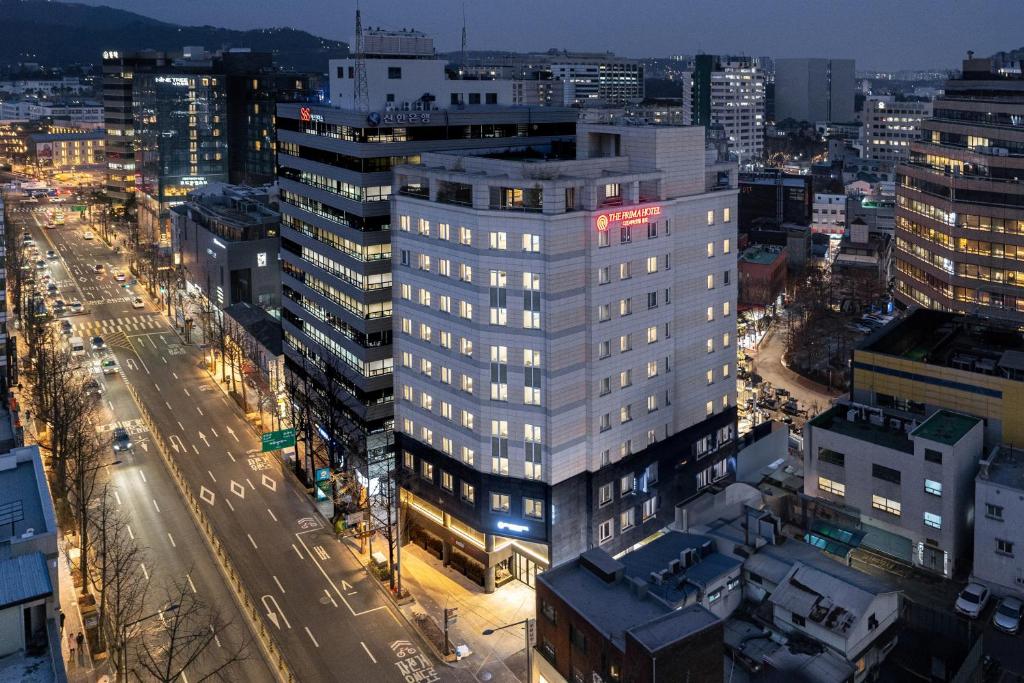 un edificio blanco alto en una ciudad por la noche en The Prima Hotel Jongno en Seúl