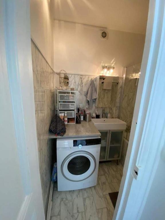 une petite salle de bains avec un lave-linge et un lavabo dans l'établissement Cosy apartment in Levallois, à Levallois-Perret