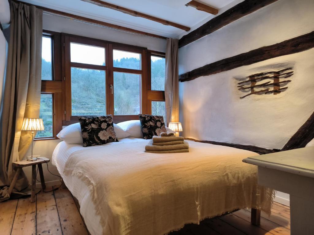 a bedroom with a large bed in a room with windows at petite maison am Mühlenberg in Monschau