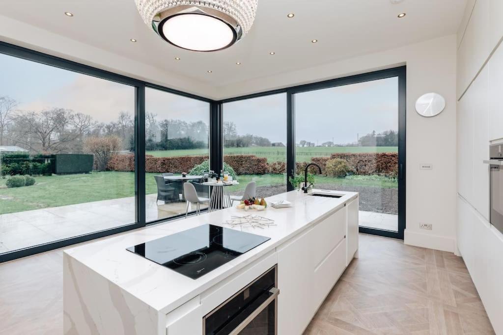 a kitchen with white countertops and large windows at Wisteria House in Marlow