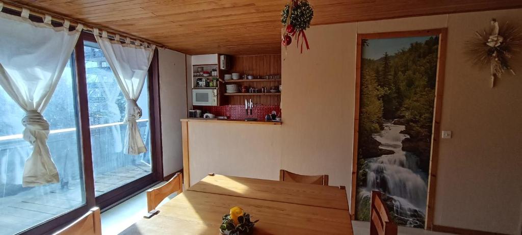 une salle à manger avec une table et une grande fenêtre dans l'établissement Large studio in Saint-Chaffrey, à Saint-Chaffrey