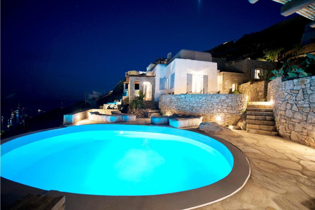 Luxury Mykonos Villa - 3 Bedrooms - Villa Vigor - Stunning Sea Views - Agios Lazaros في بسارو: مسبح في الليل مع منزل في الخلفية