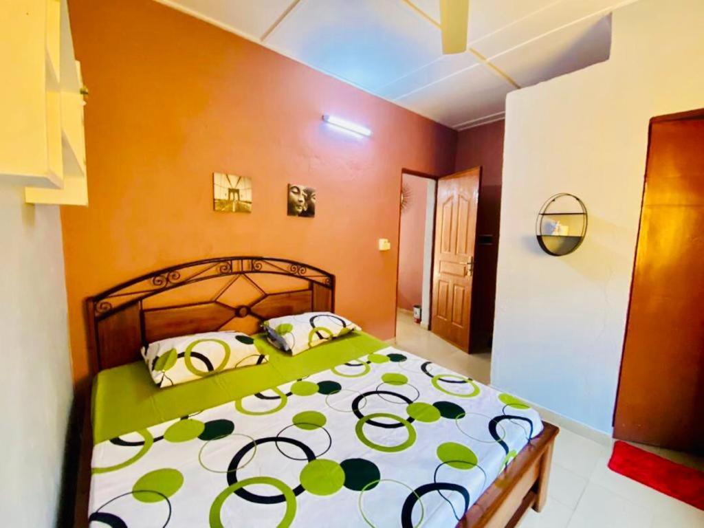 1 dormitorio con 1 cama con edredón verde y blanco en Eden Meublé en Uagadugú