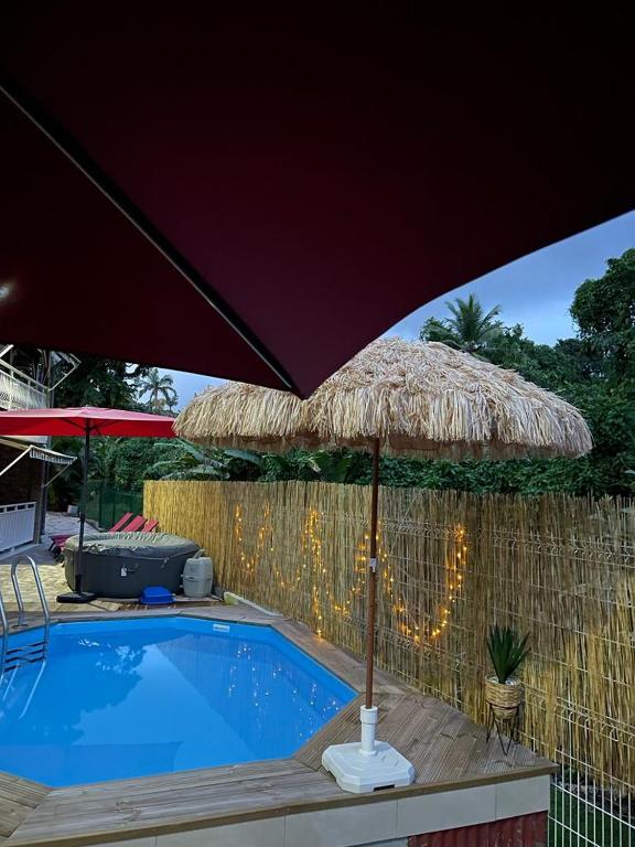 a large straw umbrella next to a swimming pool at Villa Red Palmer -sauna jacuzzi in Gros-Morne