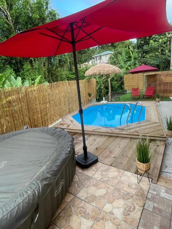 a red umbrella sitting next to a swimming pool at Villa Red Palmer -sauna jacuzzi in Gros-Morne