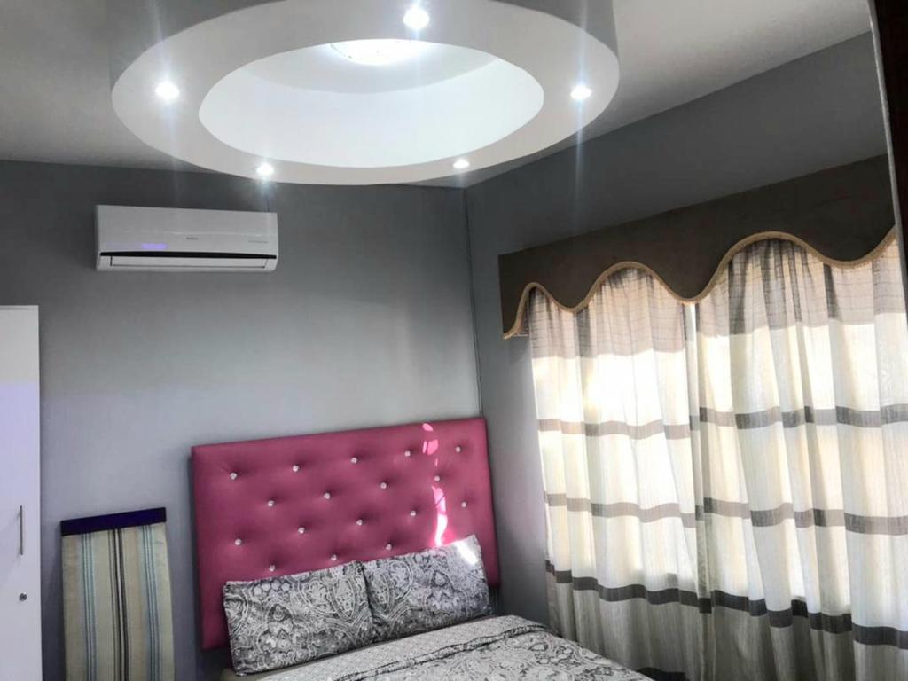 een slaapkamer met een bed met een roze hoofdeinde bij Royal Taste of Africa Apartments in Windhoek