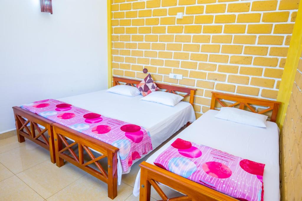 a room with two beds and a brick wall at SHYNI Guest House in Hikkaduwa
