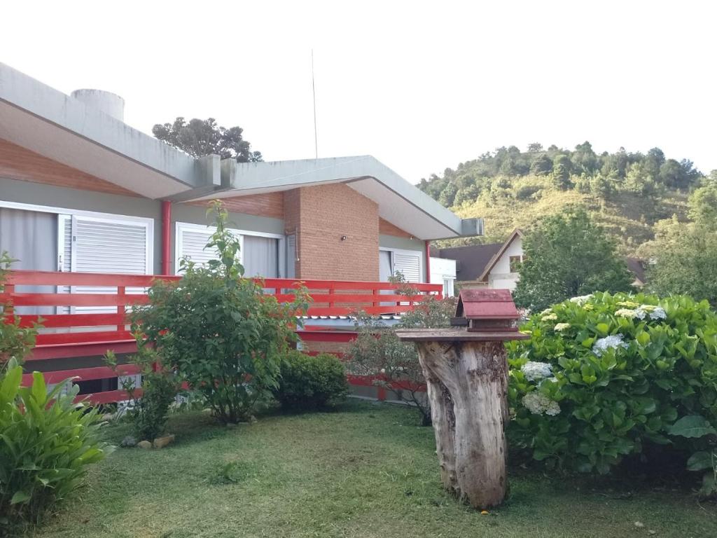 une maison avec une clôture rouge et une table dans la cour dans l'établissement Hospedagem Virginia Bracelli, à Campos do Jordão