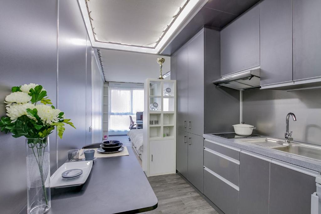 une cuisine avec un vase de fleurs sur un comptoir dans l'établissement LOKORA REIMS, à Reims