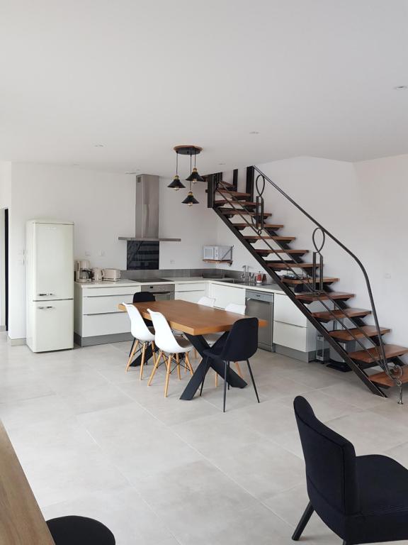 eine Küche und ein Esszimmer mit einem Tisch und einer Treppe in der Unterkunft Mon Gîte in Château-du-Loir