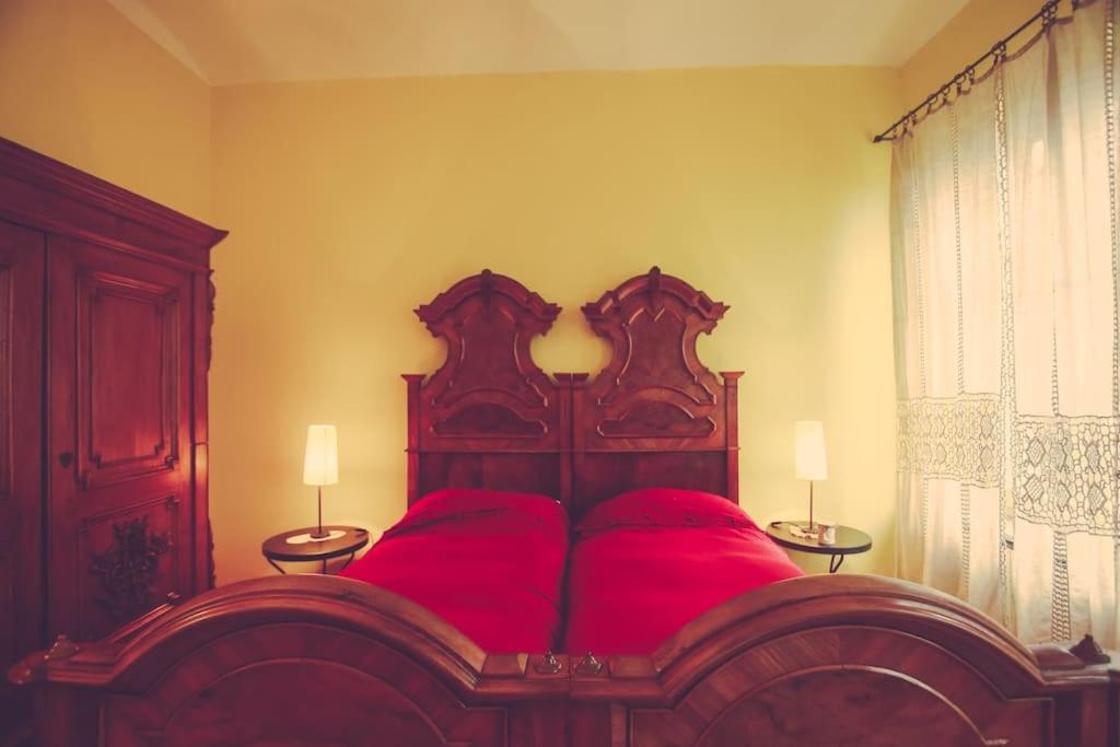 PortacomaroにあるHistoric and quiet house in the Langhe&Monferratoのベッドルーム1室(赤い大型ベッド1台、ランプ2つ付)
