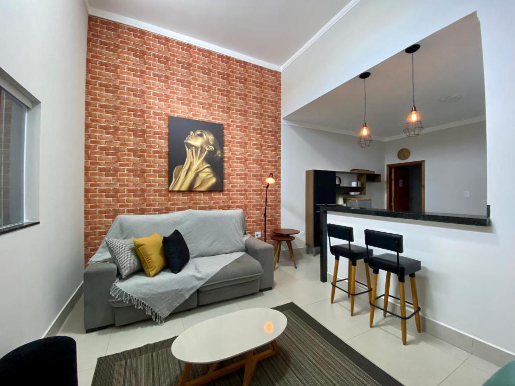 a living room with a couch and a brick wall at Casa bem Equipada 3 quartos in Marília