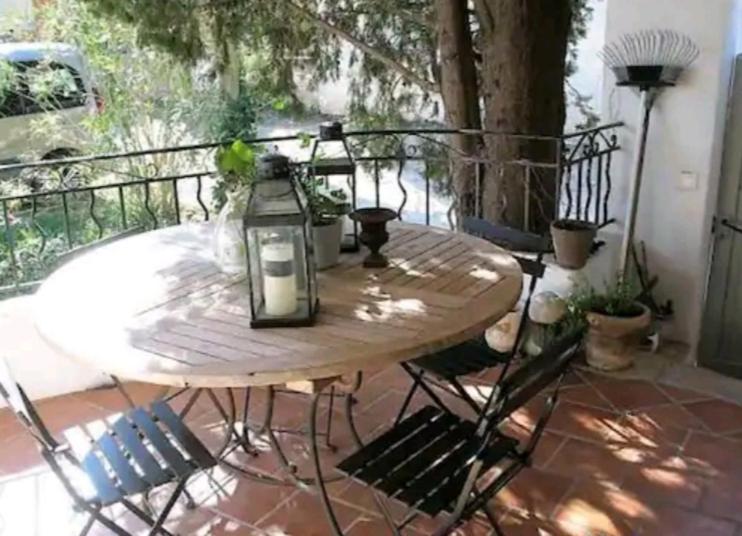 einen Holztisch mit Stühlen und eine Laterne auf einer Terrasse in der Unterkunft Grande maison en pierre dans la colline varoise in Vidauban