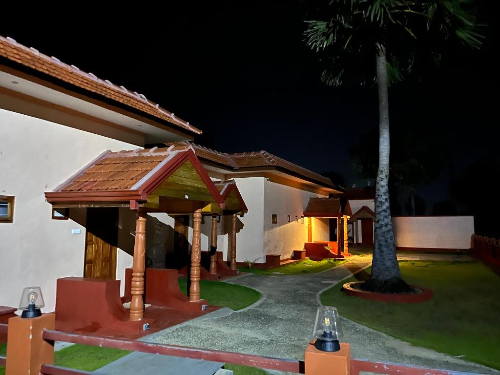 a night view of a house with a palm tree at Palm Path Resort in Jaffna