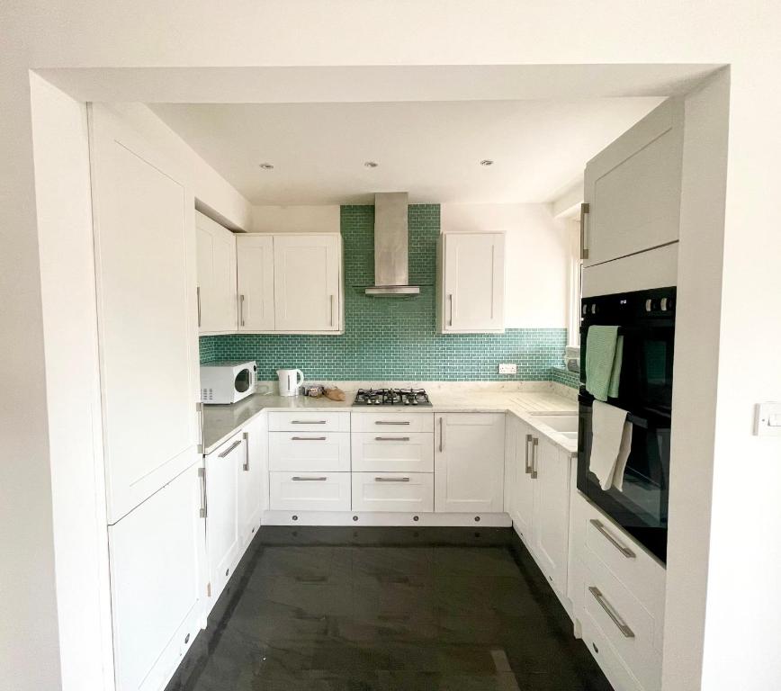 a white kitchen with white cabinets and a stove top oven at Greater London House with excellent transport in Forest Hill