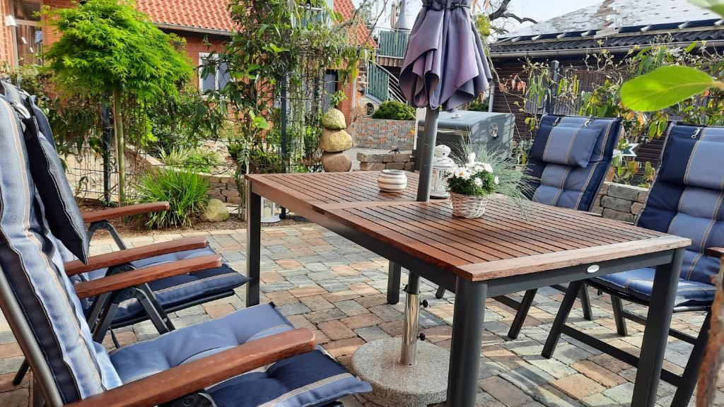 einen Holztisch mit Stühlen und einem Sonnenschirm auf einer Terrasse in der Unterkunft Ferienwohnung Taubenschlag mit Sauna in Kirchlinteln