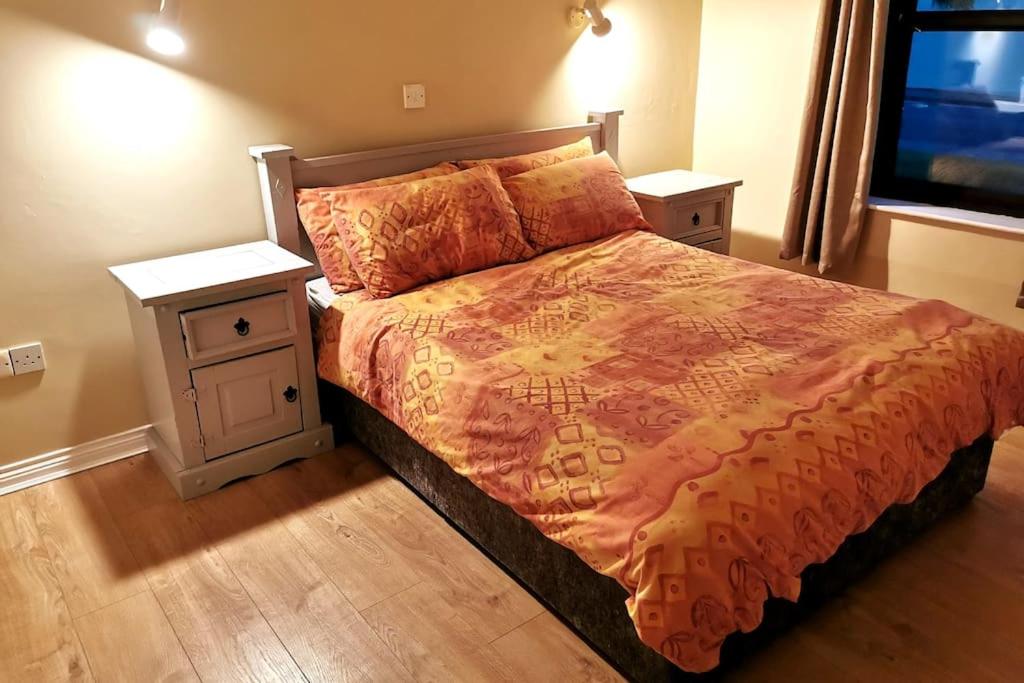 um quarto com uma cama grande e 2 mesas de cabeceira em Bungalow by the Beach em Tramore