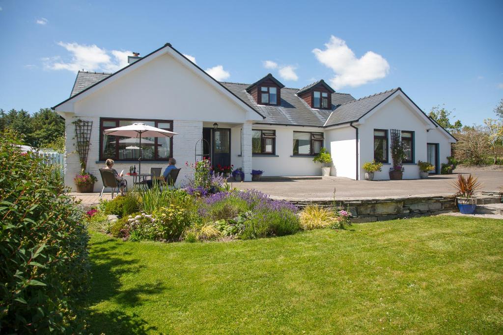 een wit huis met een persoon die onder een paraplu zit bij Donemark Rise B&B in Bantry