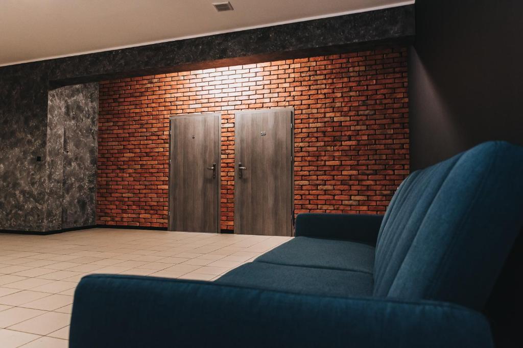 a room with a blue couch and a brick wall at Noclegi Na Końcu Świata Bielpon in Przemyśl
