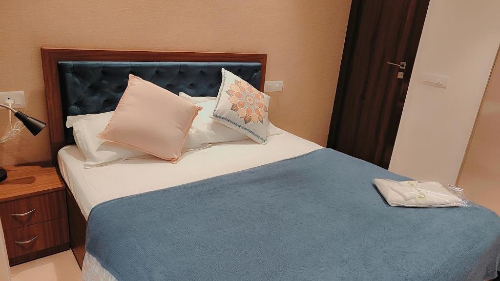 a bedroom with a bed with a blue blanket and pillows at Trendy1BR+smart kitchen +Living room+1.5 toilets in Mumbai