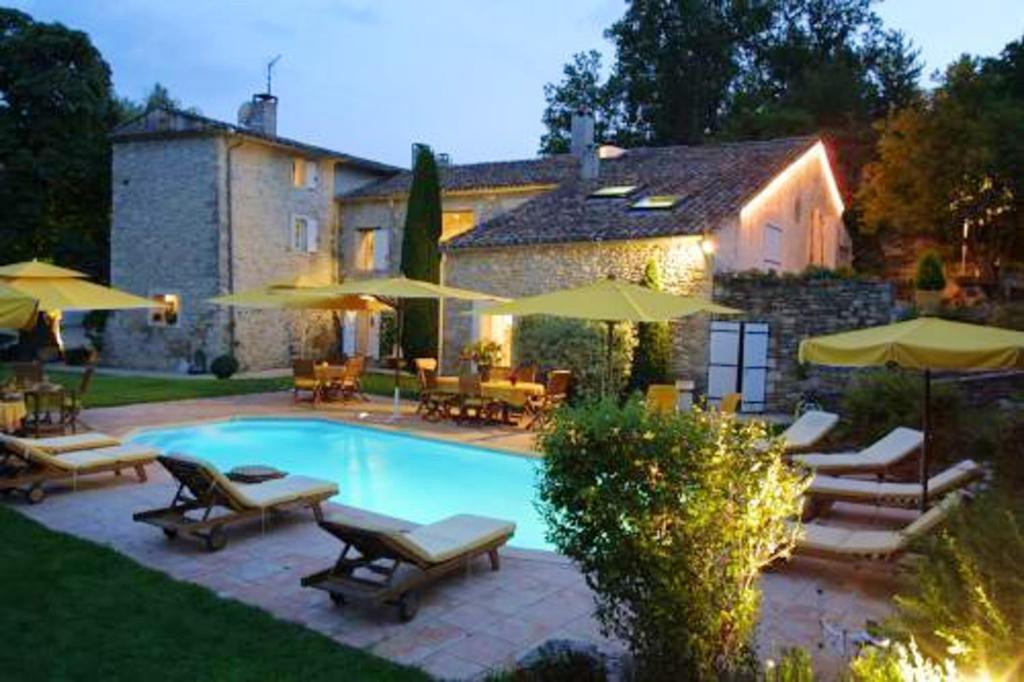 a pool with chairs and umbrellas in front of a house at Studio avec piscine partagee jardin clos et wifi a Forcalquier in Forcalquier