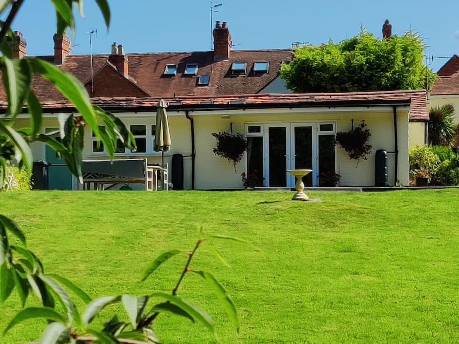 uma casa com um relvado verde em frente em The Nook located in a beautiful garden setting with parking em Stratford-upon-Avon