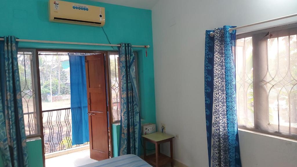a room with a bed and a window with a balcony at Casa baptista in Candolim