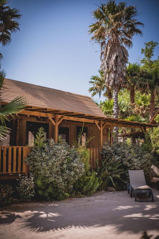 a wooden house with a chair and a palm tree at Les Prairies de la Mer in Grimaud