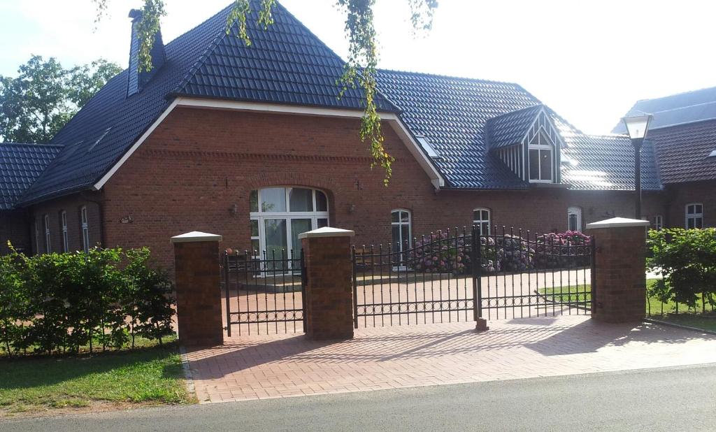 a red brick house with a black fence at Ferienwohnung Möllers Hof in Petershagen