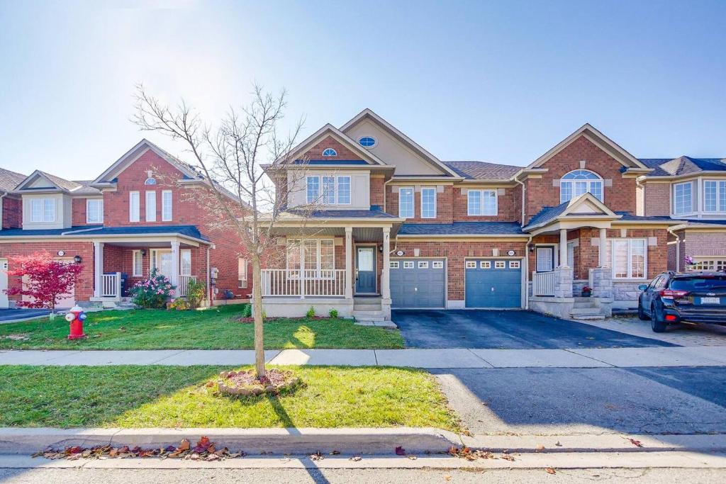 a large brick house with a car parked in the driveway at Tasha Dr Suites, 4BR in Mississauga