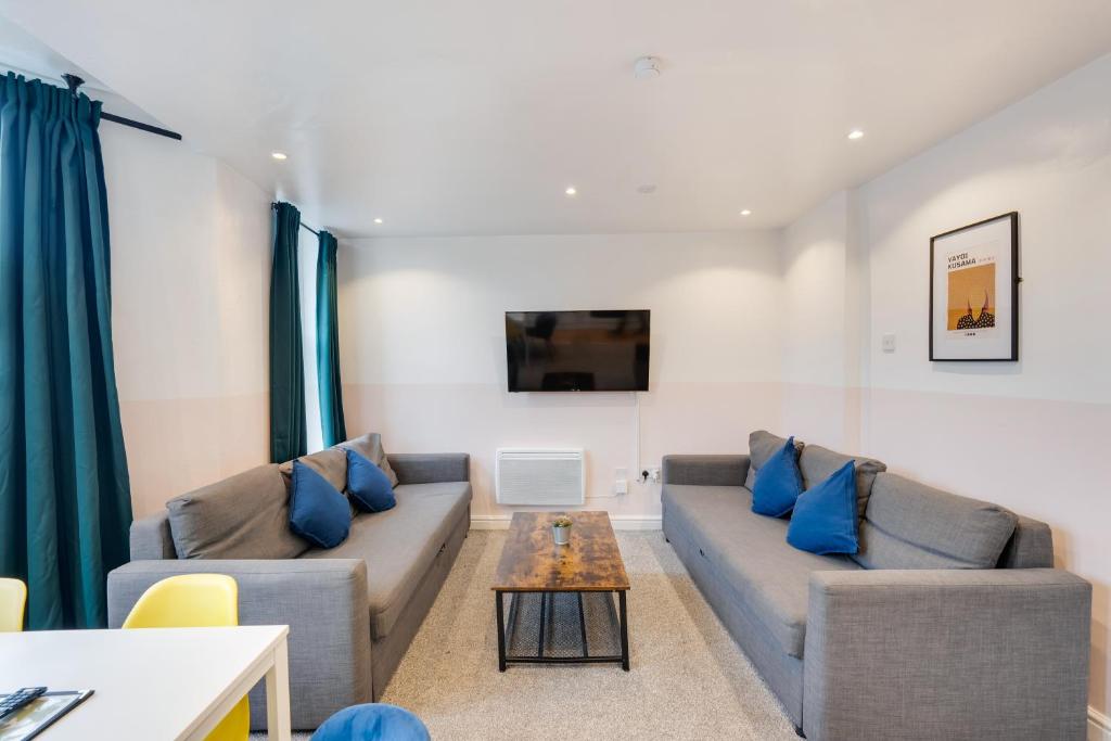 a living room with two couches and a table at Duplex Apartment For Up to 13 Near City Centre in Cardiff