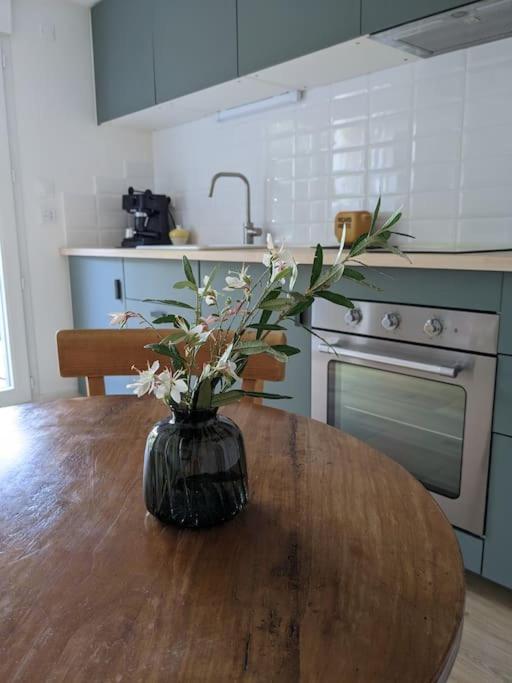 un vase avec des fleurs sur une table en bois dans une cuisine dans l'établissement Appartement cosy près de Toulouse et du Gers, à Toulouse