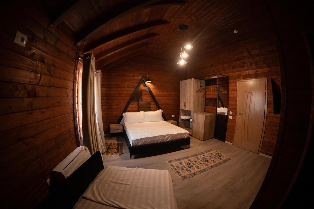 1 dormitorio con 1 cama en una habitación de madera en Hotel Avdi Rexha, en Kolgecaj