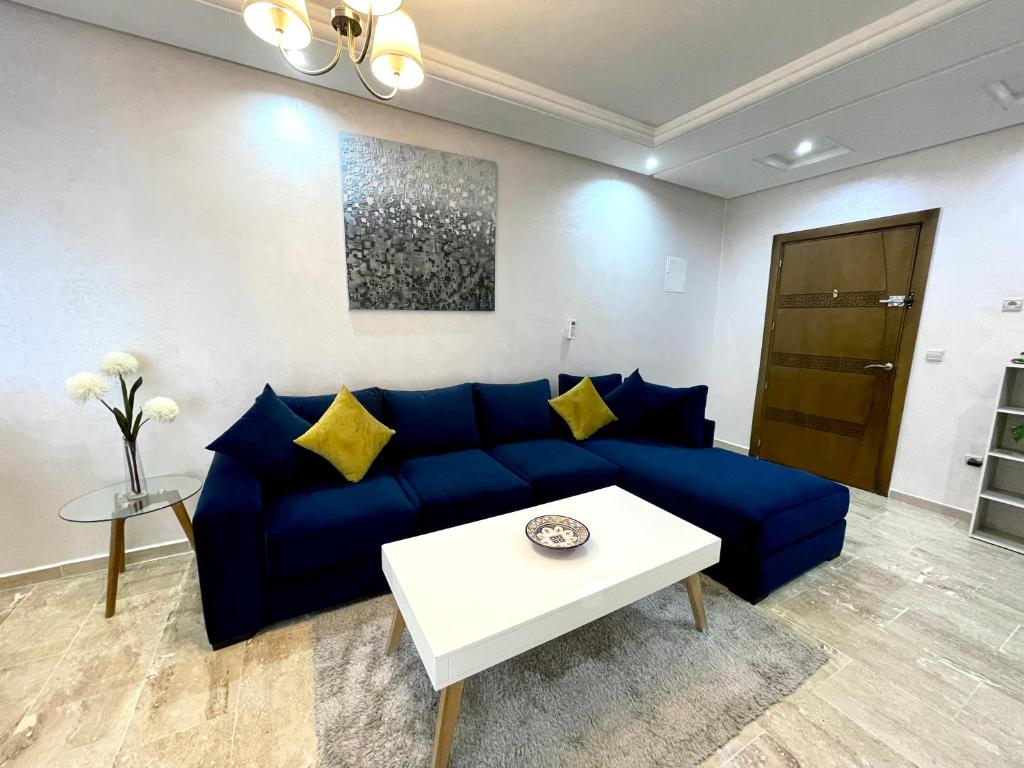 ein Wohnzimmer mit einem blauen Sofa und einem Tisch in der Unterkunft Appartement Tanger Moulay Ismail in Tangier