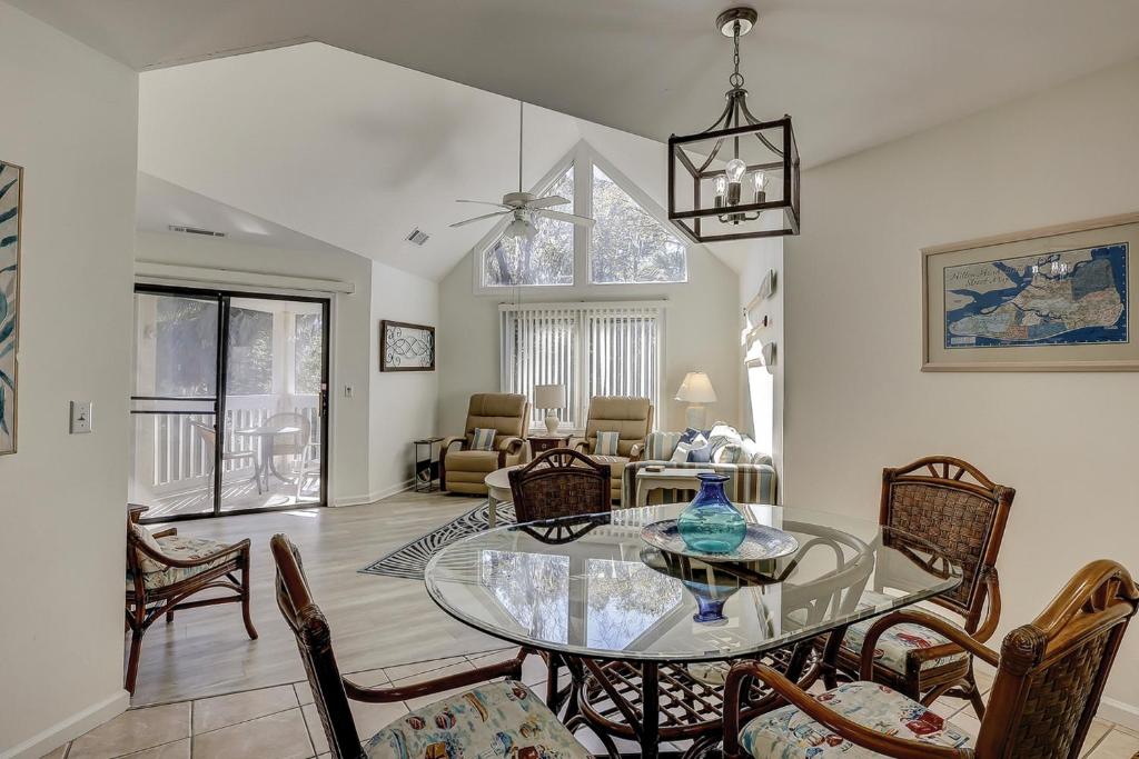uma sala de estar com uma mesa de vidro e cadeiras em Colonnade Club 206 em Hilton Head Island
