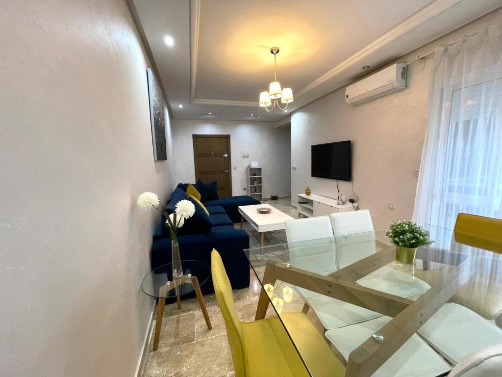 a living room with a blue couch and a glass table at Appartement Tanger Moulay Ismail in Tangier