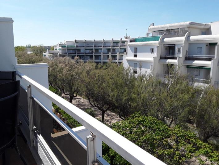 - un balcon d'un bâtiment avec des arbres et des buissons dans l'établissement Studio cabine parking et clim 100 m de la plage, à La Grande Motte