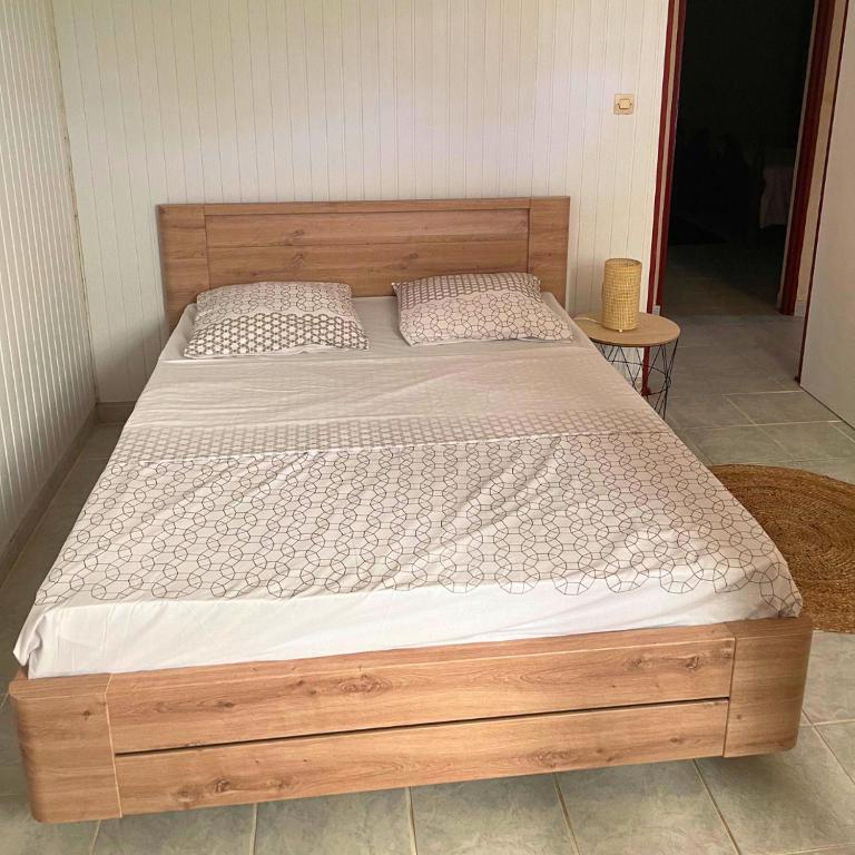 a bed in a bedroom with a wooden bed frame at Villa Red Palmer -sauna jacuzzi in Gros-Morne