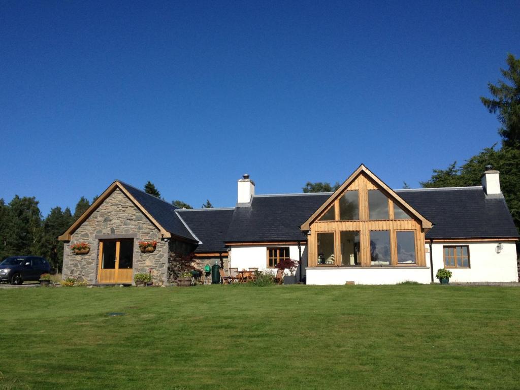 a house with a large lawn in front of it at Drumguish Cottage in Kingussie
