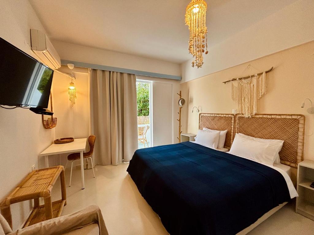 een slaapkamer met een bed, een bureau en een televisie bij Afroditi Junior Suites in Archangelos