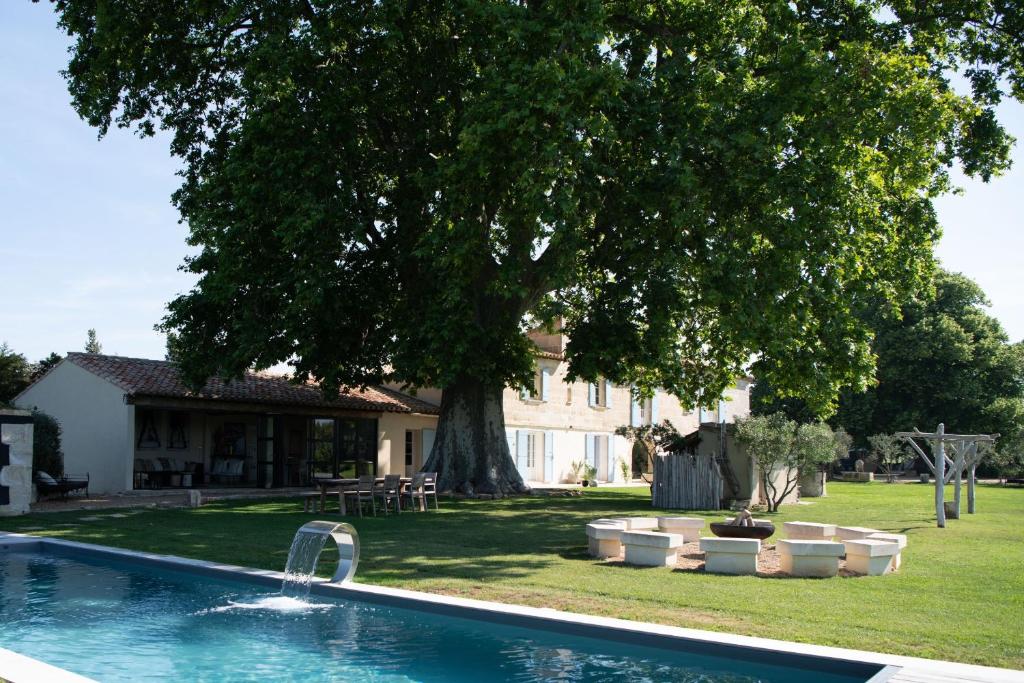 a swimming pool in front of a house with a tree at Mas d images styled by Scapa Home in Arles