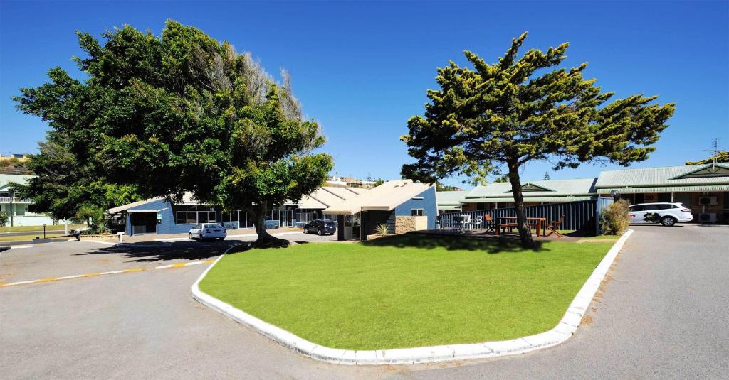 a small grassy area in a parking lot with two trees at Abrolhos Reef Lodge in Geraldton