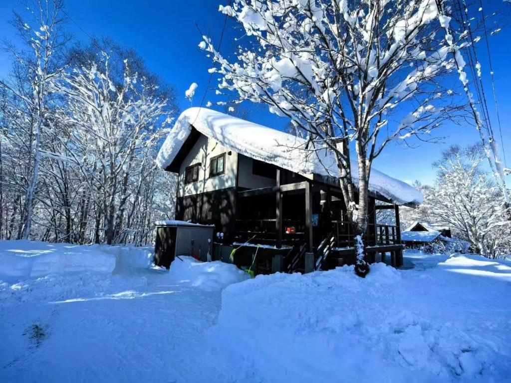 a house covered in snow next to a tree at Slow House Niseko in Niseko