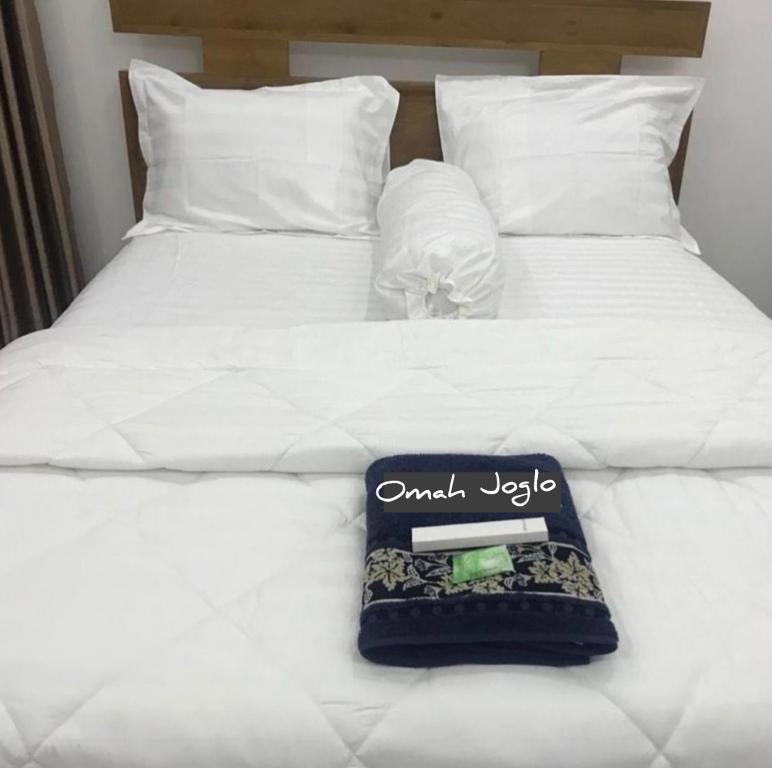 um close-up de uma cama branca com um livro sobre ela em Omah Joglo Pantai Pulau Merah em Pasanggaran
