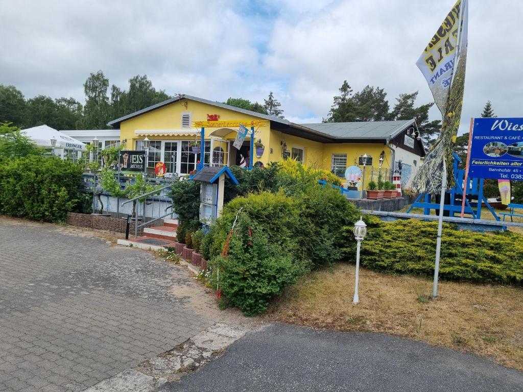 een geel huis met een parkeermeter ervoor bij Pension Wiesenperle in Trassenheide