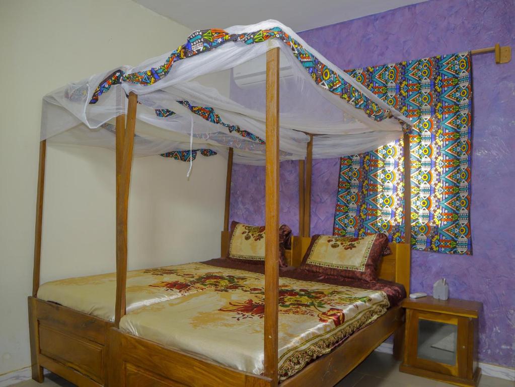 a bed with a canopy in a room at La Case a Mamy in Nianing