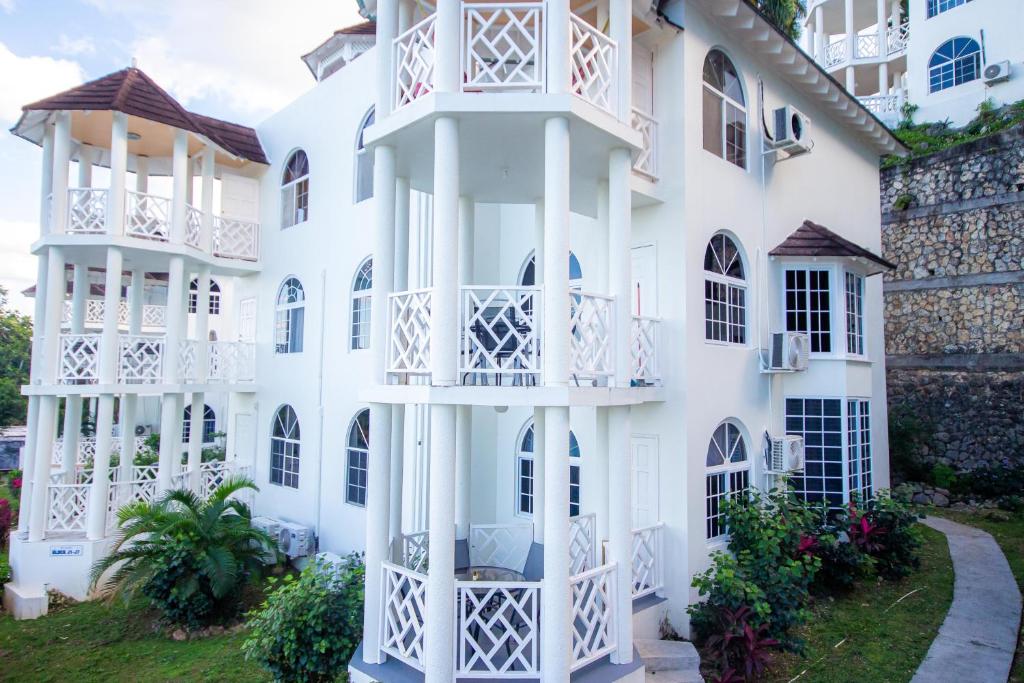 a white building with balconies and a yard at Ocho Rios Ocean Front Luxury Studio Sky Castles 24 hrs sleeps 2 in Ocho Rios